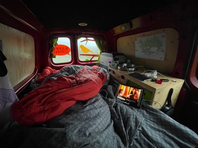 Inside of camper with bed unfolded with ipad playing Downton Abbey