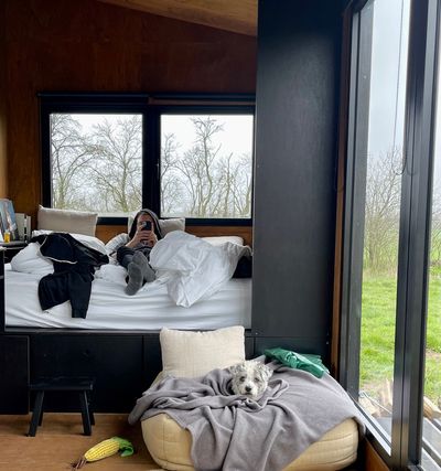 Morning view of my partner in the platform bed lying with his feet facing me. My small terrier dog is lying on a large pillow in front of the bed looking at me